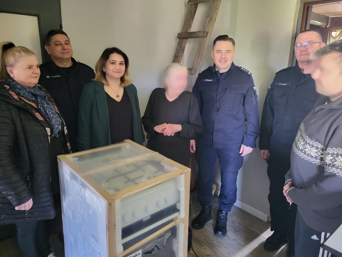 przedstawiciele policji, gopsu i dwoje mieszkańców przed nimi kuchenka gazowa