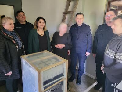 przedstawiciele policji, gopsu i dwoje mieszkańców przed nimi kuchenka gazowa