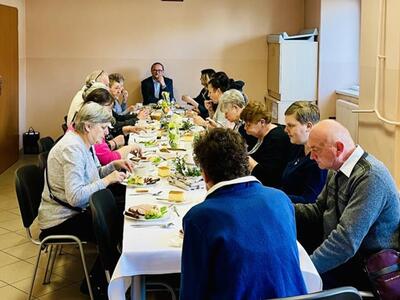 Osoby na wspólnym poczęstunku przy stole.