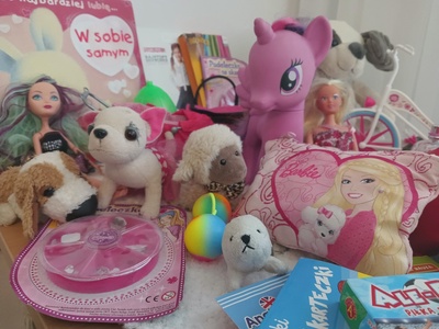 Zbiorcze zdjęcie zabawek typowyh dla dziewczynki: torebka różowa, lalki barbi, różowy jednorożec, 3 pieski pluszowe