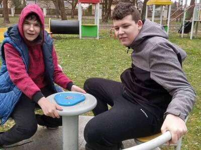 Dwóch chłopców kręci się na karuzeli na placu zabaw w parku.
