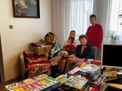 Mieszkańcy Domu, organizator akcji i dyrektor DPS, siedzący wśród zebranych darów w trakcie akcji.