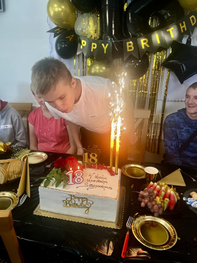 Młody chłopiec zdmuchuje świeczki z tortu urodzinowego.