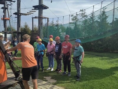 Grupa mieszkańców przygotowuje się do wyjścia w park linowy.