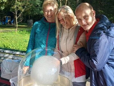 Dwie panie kucharki przygotowują watę cukrową. Młody mężczyzna przytula się do jednej z pań.