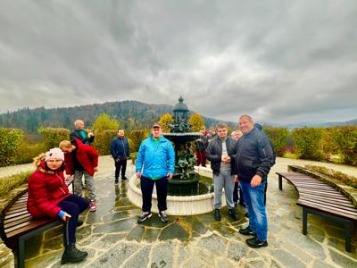 Grupa uczestników wycieczki stoi przy fontannie.