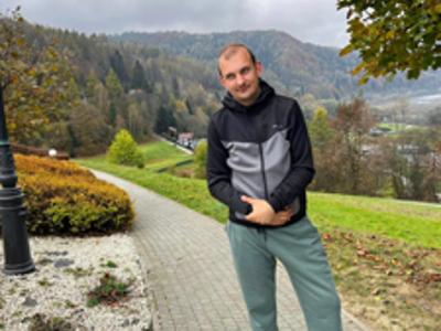 Młody mężczyzna pozuje do zdjęcia na ścieżce ogrodowej w ogrodach sensorycznych.