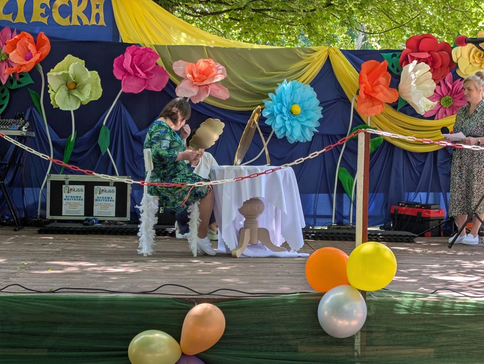 Młoda kobieta przebrana siedzi za stołem na scenie.