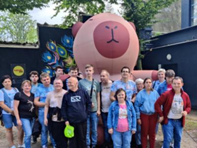 Grupa uczestników wycieczki pozuje do zdjęcia na tle figury na placu zabaw w ZOO w Łodzi.