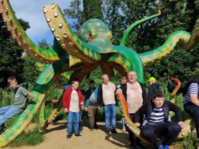 Grupa mieszkańców Domu pozuje do zdjęcia na tle ogromnej rzeźby ośmiornicy w ZOO w Łodzi.