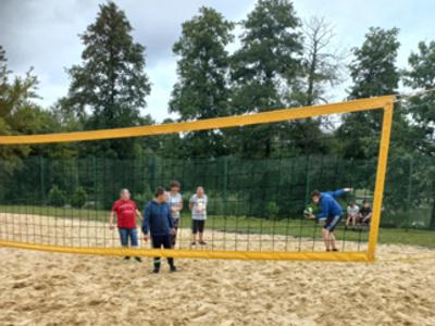 Grupa mieszkańców Domu gra w siatkówkę plażową