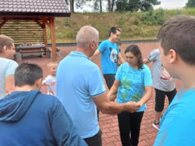 Grupa mieszkańców Domu tańczy w kółeczku do muzyki biesiadnej