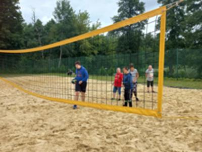 Grupa mieszkańców Domu gra w siatkówkę plażową