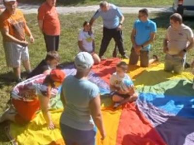 Grupa mieszkańców Domu bawi się z chustą animacyjną