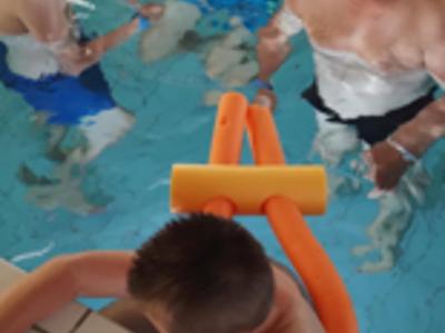 Grupa mieszkańców DPS pozuje do zdjęcia z basenu.