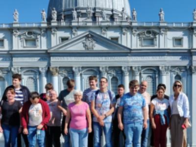 Zdjęcie grupowe uczestników wycieczki na tle miniatury budynku w Parku Miniatur