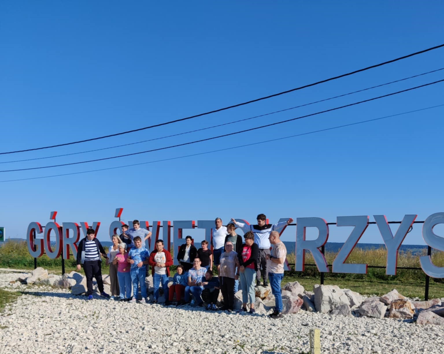 Zdjęcie grupowe uczestników wycieczki na tle napisu Góry Świętokrzyskie