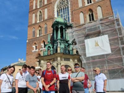 Grupa mieszkańców pozuj do zdjęcia na tle Bazyliki Mariackiej