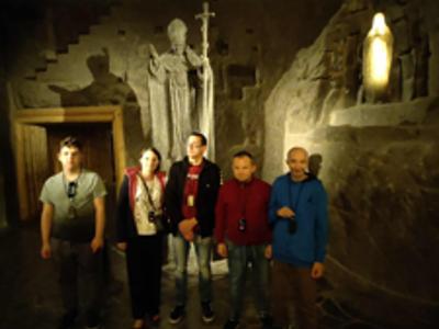 Grupa uczestników wycieczki pozuje do zdjęcia przed pomnikiem J.P. II w Kopalni soli Wieliczka