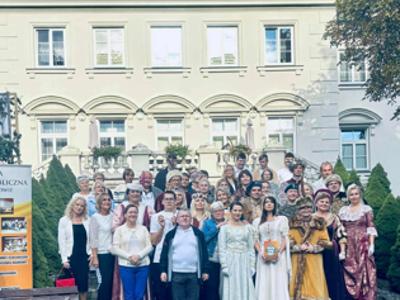 Grupa mieszkańców, pracowników Domu i lektorów wydarzenia na tle Pałacu