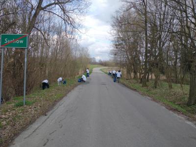 Na zdjęciu znajdują się uczestnicy akcji Sprzątamy u siebie, którzy sprzątają teren przy głównej drodze.