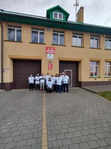 Na zdjęciu znajdują się uczestnicy akcji Sprzątamy u siebie na tle remizy strażackiej.
