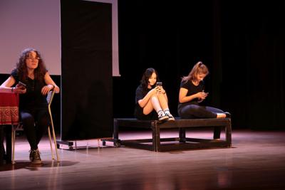 Fragment występu teatralnego w ramach LKA Finał Wojewódzki TEATR 2024 - na scenie 3 aktorki, zamyślone, zapatrzone w telefony komórkowe.