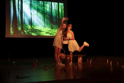Fragment występu teatralnego w ramach LKA Finał Wojewódzki TEATR 2024 - scena, w której dwie młode kobiety robią sobie selfie na tle lasu.
