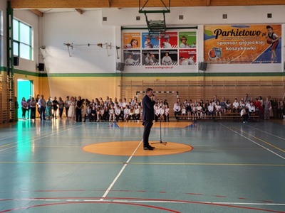 Pan Dyrektor Dariusz Fijałkowski, sztandar szkoły, w tle uczniowie