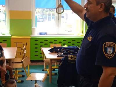 Pan ze Straży Miejskiej prezentuje kajdanki