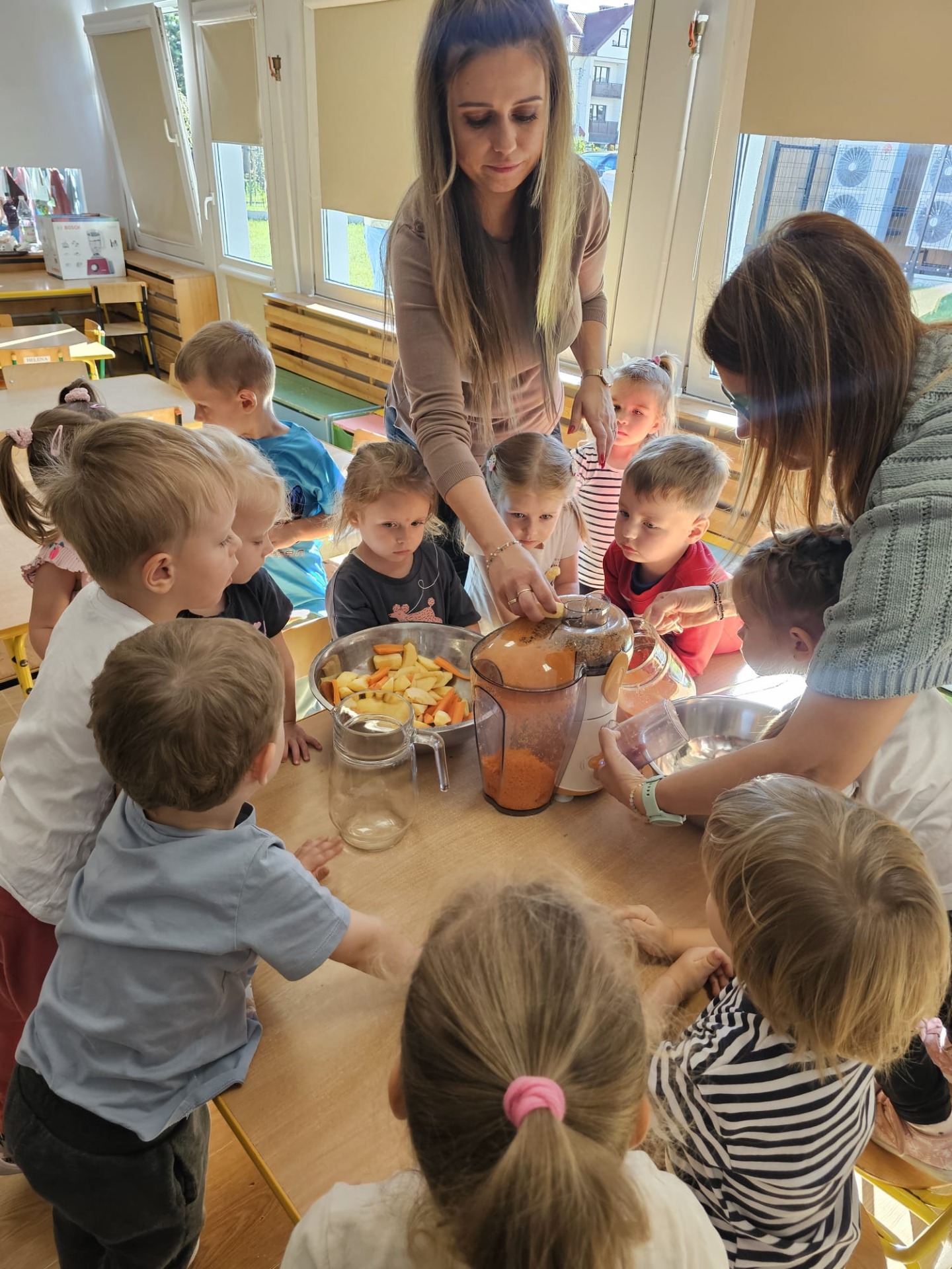 Dzieci pomagające przygotować sok owocowo-warzywny.