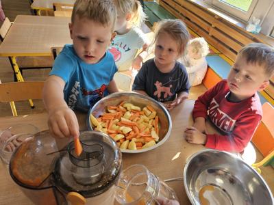 Dzieci pomagające przygotować sok owocowo-warzywny.
