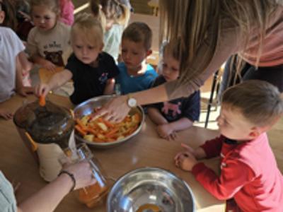 Dzieci pomagające przygotować sok owocowo-warzywny.