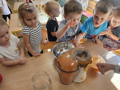 Dzieci pomagające przygotować sok owocowo-warzywny.