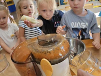 Dzieci pomagające przygotować sok owocowo-warzywny.