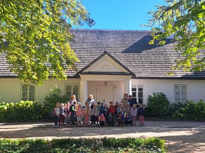 Grupa przedszkolaków na tle dworku w Żelazowej Woli.