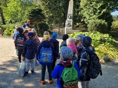 Grupa przedszkolaków na tle parku.