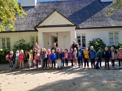 Grupa przedszkolaków na tle dworku w Żelazowej Woli.