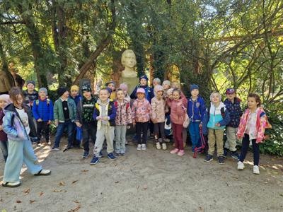 Grupa przedszkolaków na tle parku.