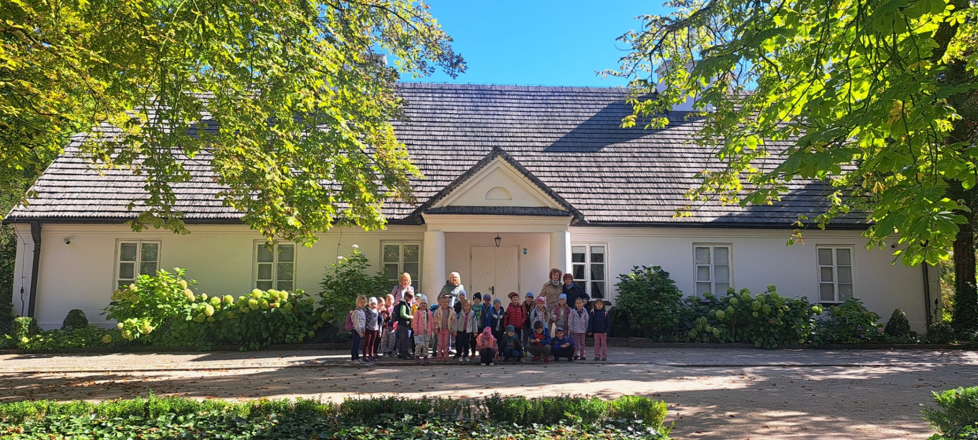 Grupa przedszkolaków na tle dworku w Żelazowej Woli.
