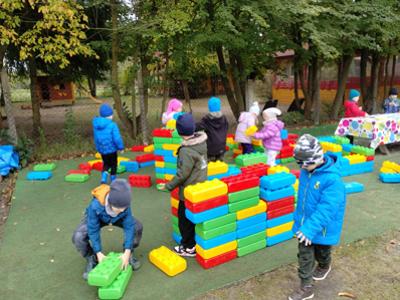 Dzieci podczas zabaw dużymi klockami na świeżym powietrzu.