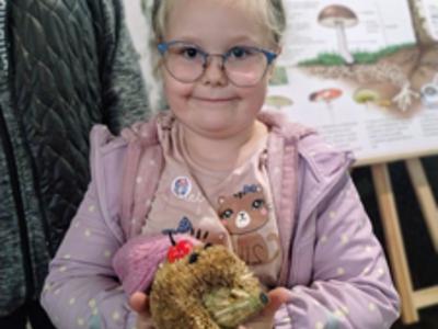 Uśmiechnięta dziewczynka pozująca z eksponatem jeża.