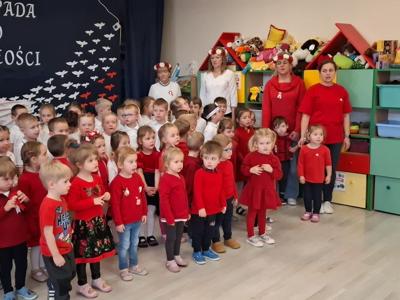 Grupa przedszkolaków wraz z wychowawcami podczas śpiewania hymnu narodowego.