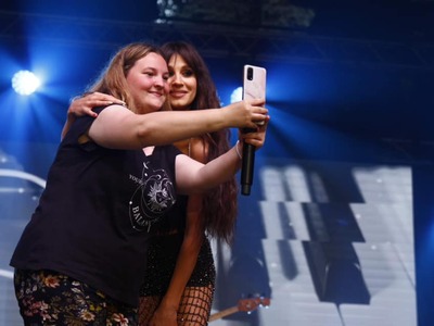 Zdjęcie Sylwii Grzeszczak podczas pozowania do pamiątkowych zdjęć z fanką zaproszoną na scenę podczas koncertu
