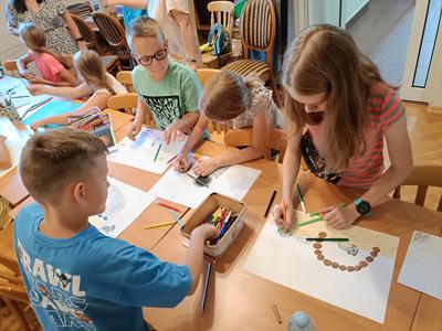 Grupa dzieci kończy pisać i rysować swoje opowiadanie