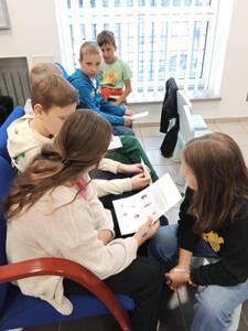 Grupa dzieci rozwiązuje zadania w Banku Polskim w Koluszakch