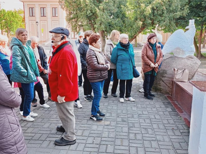 Grupa seniorów wraz z przewodnikiem na wycieczce w Łęczycy