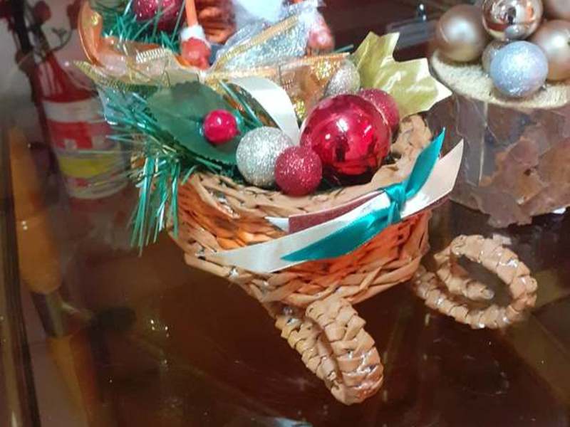 Święty Mikołaj siedzący w wiklinowych, zdobionych saniach