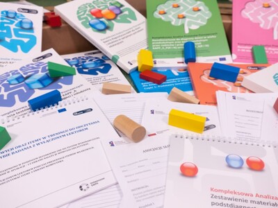 podręczniki i materiały do terapii wraz z rozsypanymi klockami dla dzieci na podłodze