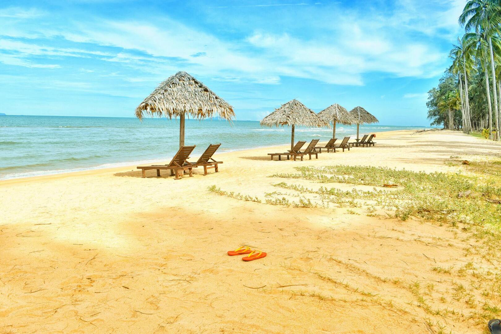 pomarańczowe klapki na plaży, parasole, leżaki - Zdjęcie dodane przez Pixabay: https://www.pexels.com/pl-pl/zdjecie/lezaki-pod-parasolem-w-shoreline-531035/